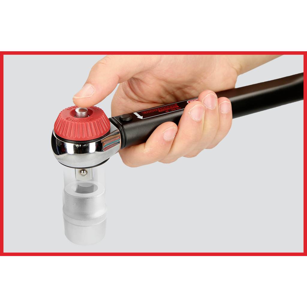 A hand is holding a red and black handle attached to a transparent container.