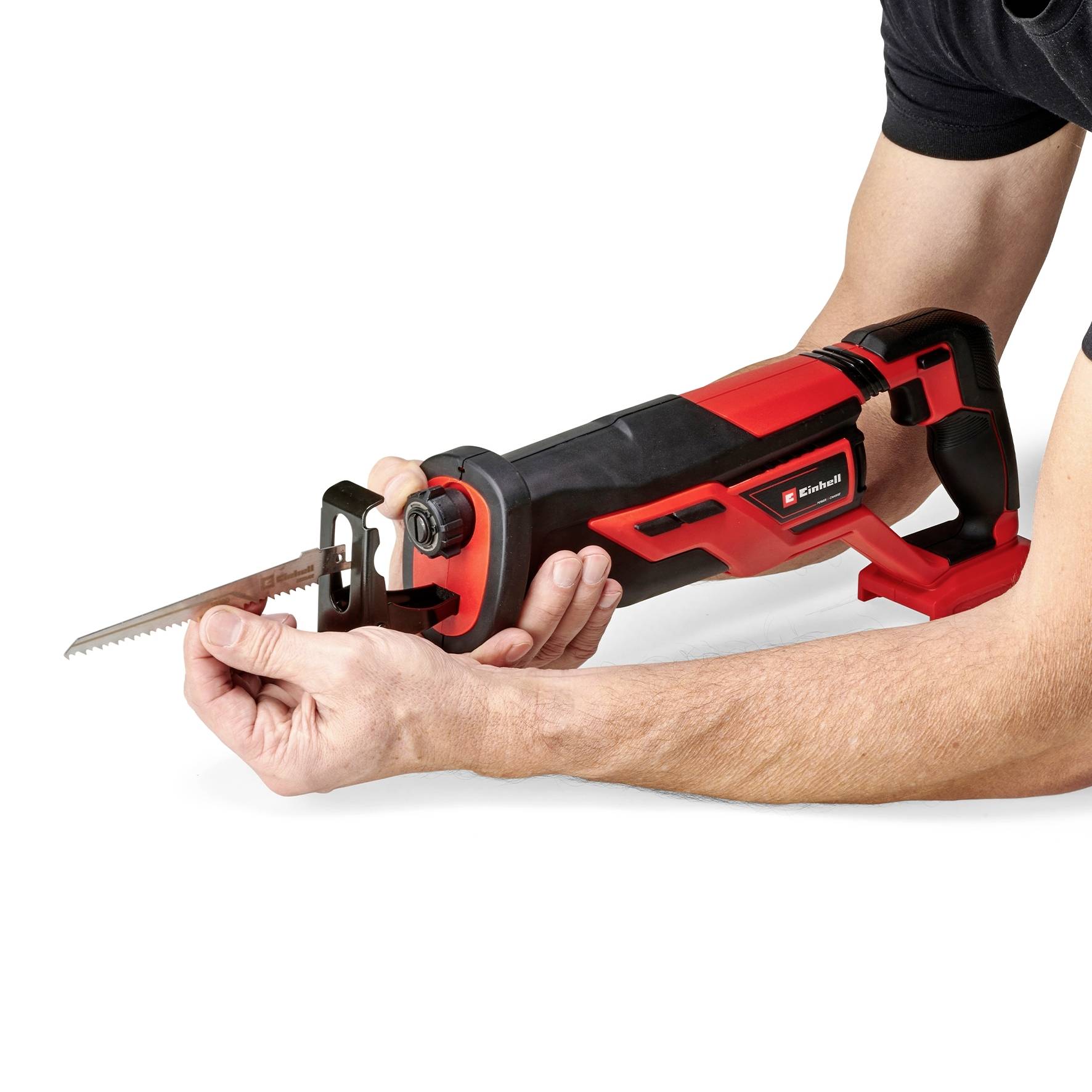 A person is holding an electric reciprocating saw with a red handle, pointing the blade to the side. They are ready for use.