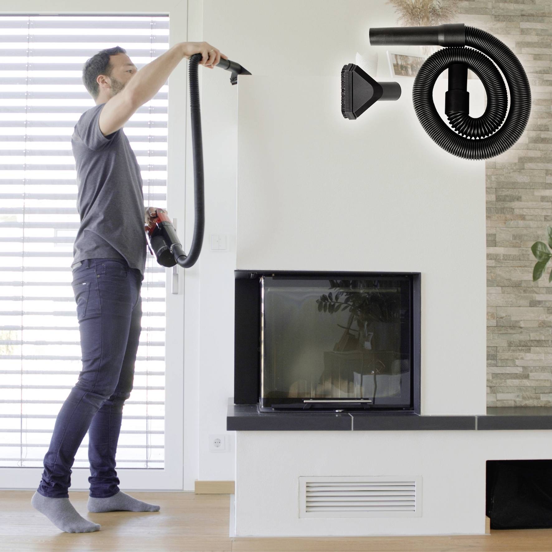 A person is installing a vacuum cleaner hose on a wall mount beside a fireplace.