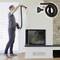A person is installing a vacuum cleaner hose on a wall mount beside a fireplace.