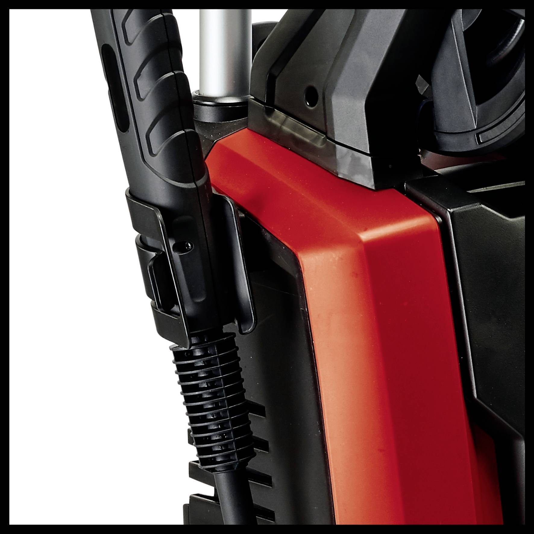A section of a pressure washer with black and red components and an attached hose.