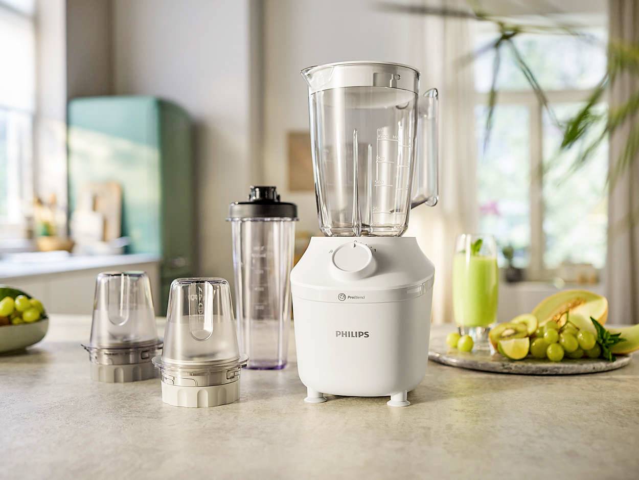 Mixer with accessories on a kitchen worktop, with a bright kitchen in the background featuring a fruit bowl and green walls.