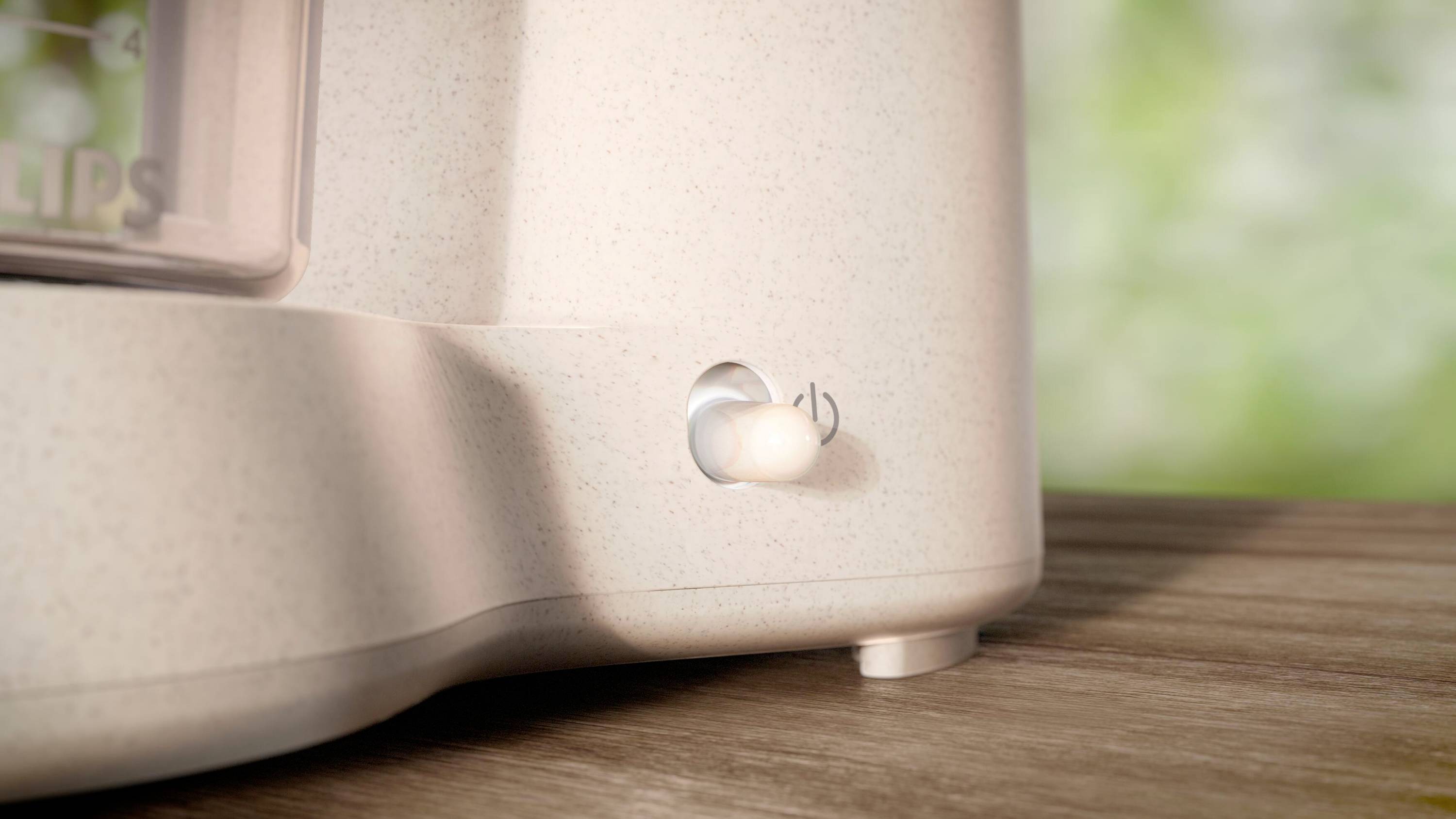 Toaster with switch in close-up. The focus is on an illuminated on/off switch. The background is blurred.