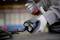 A person wearing grey gloves is holding the plug of an electrical cable, presumably in a workshop environment.