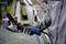 A person is holding a Bosch angle grinder in their hand. Metal parts are visible in the background of a workshop.