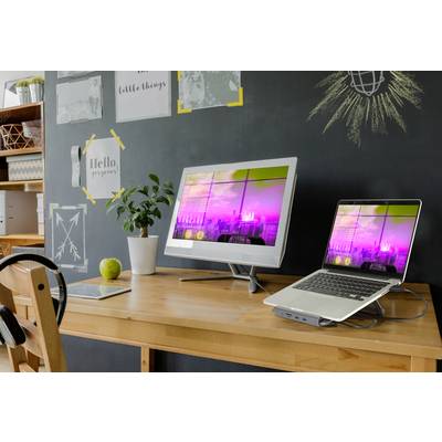 Home office with large monitor and laptop on wooden desk. Black wall with doodles in the background, plants and office supplies.