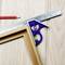 Wooden angle and blue protractor with spirit level on light wooden table next to a red pencil.