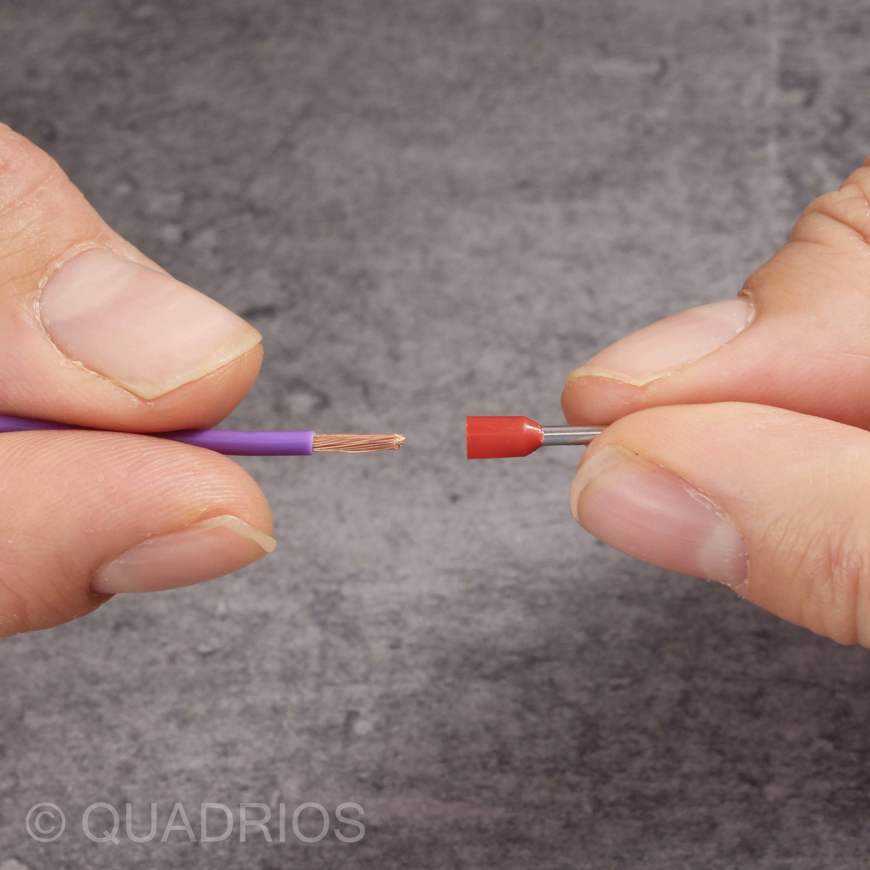 Two hands are holding a red and black connector and a copper wire.