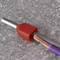 A grey cable with a red plastic sheath encases exposed copper wires on a grey, speckled surface.