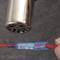 A silver metal tube at the top with a red cable surrounded by blue heat-shrink tubing underneath. A hand is holding the cable.