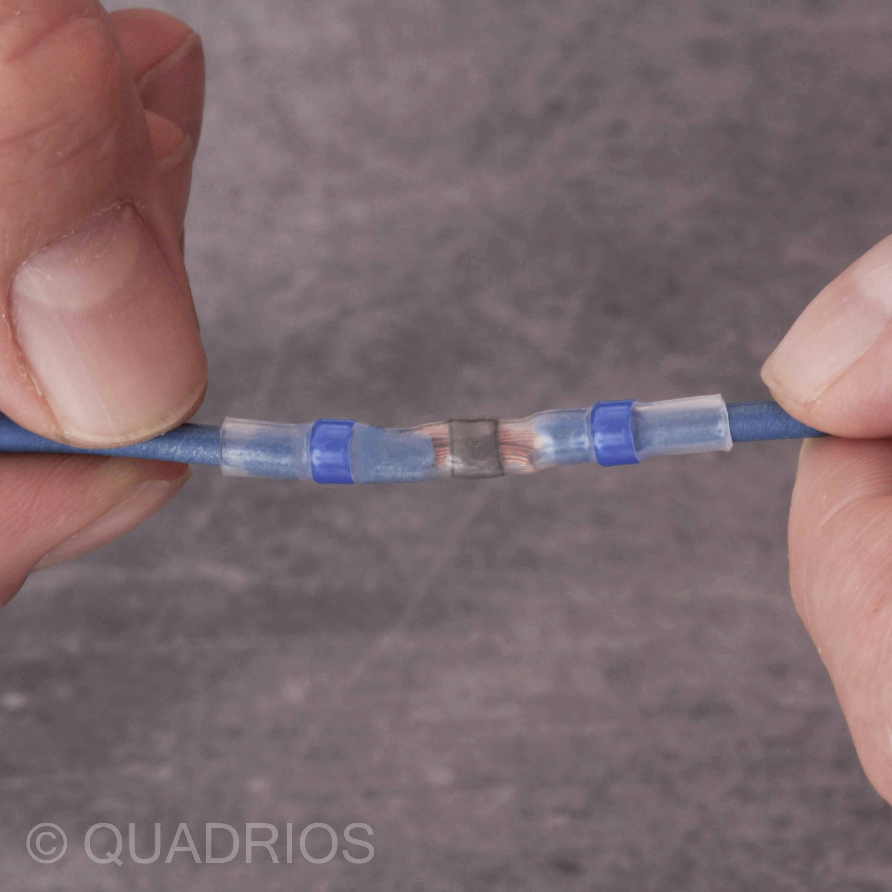 Two hands are holding a blue cable with a transparent, blue heat-shrink connection; brand logo 'QUADRIOS'.