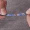 Two hands are holding a blue cable connected to a heat-shrink sleeve. The connection is protected by transparent and blue sheaths.