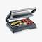 An open tabletop grill with grilled vegetables, including courgettes, peppers and mushrooms, on the ridged grilling surface.