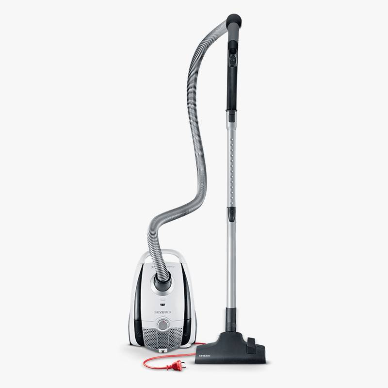 A vacuum cleaner with a red cable and white casing stands on a grey background. The hose is connected to the main body.