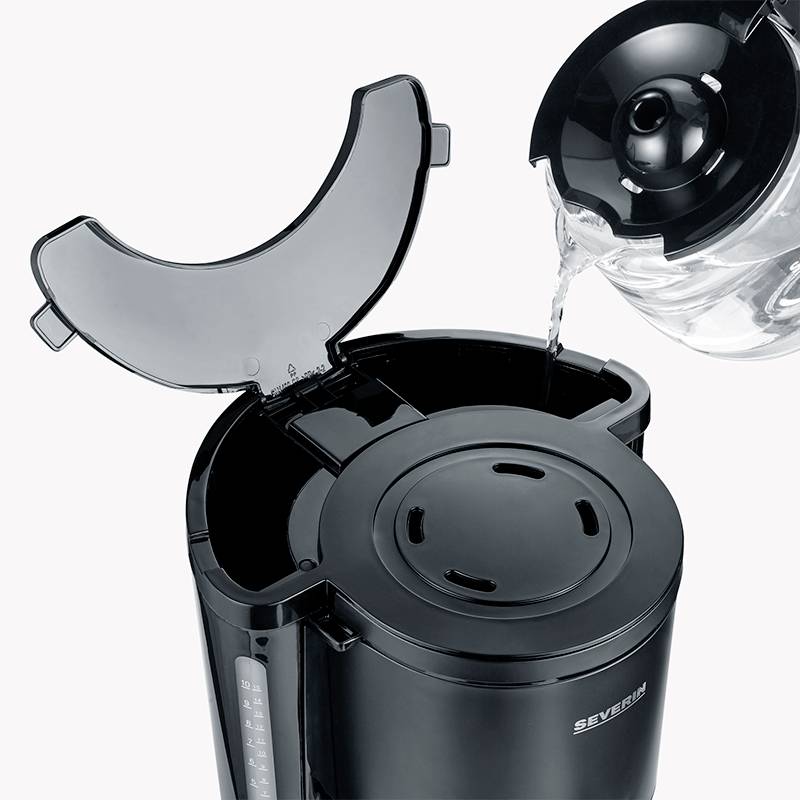 Electric kettle with lid open, water being poured from a transparent container. A water level indicator visible on the left.