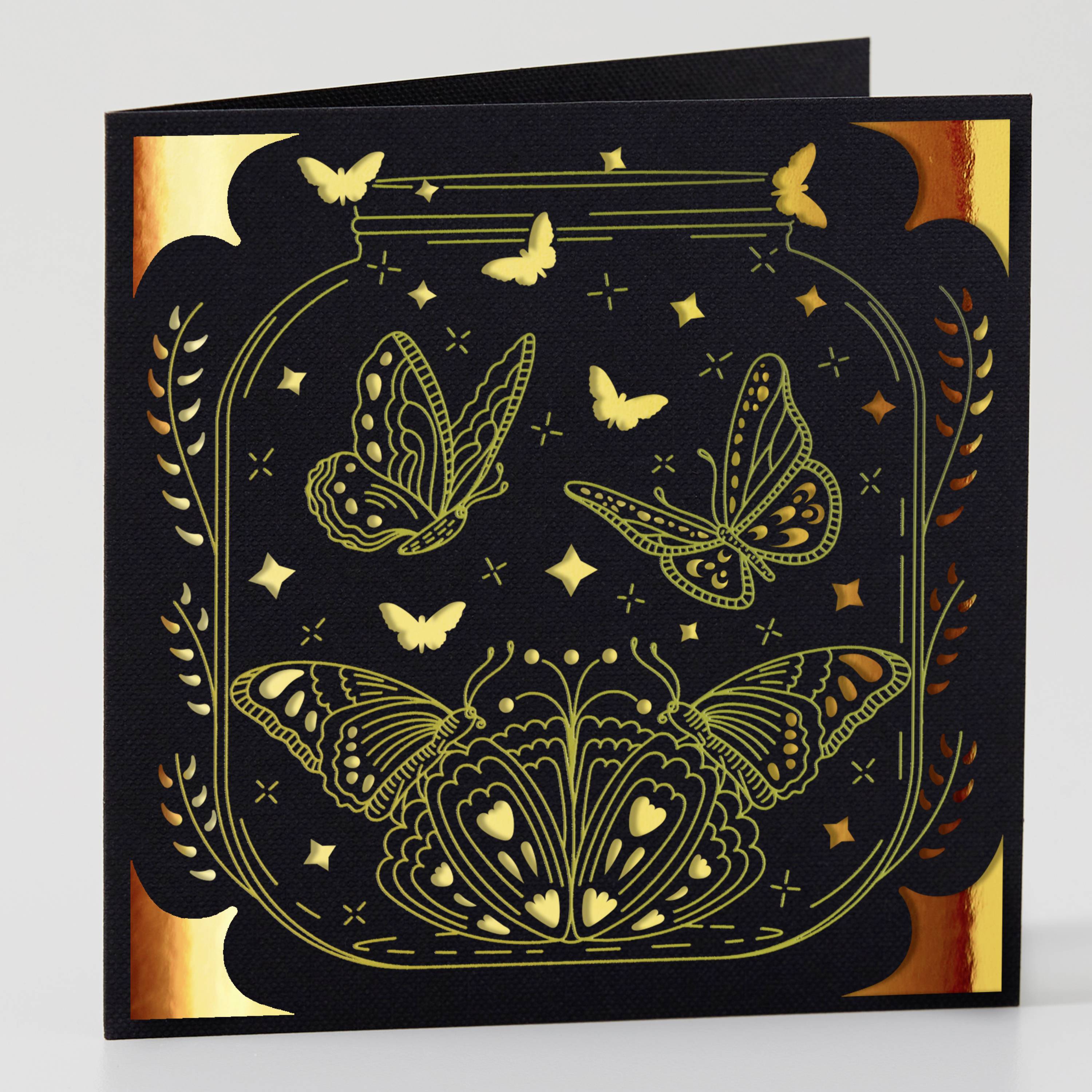 Black card with golden butterflies and a stylised glass, surrounded by star-like shapes and decorative corners.