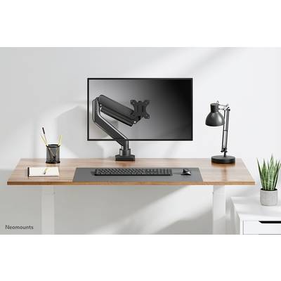 Height-adjustable desk with monitor mount, monitor, keyboard, lamp, and pen holder; minimalist home office.