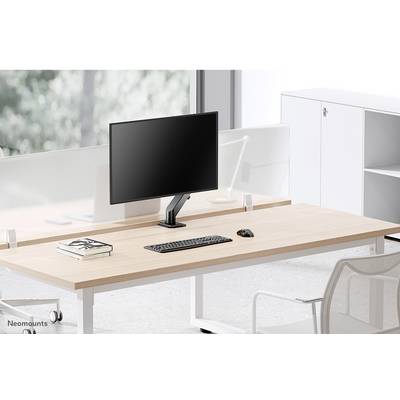 A modern desk with a wooden top, featuring a computer monitor, keyboard, and mouse; an office chair and shelving unit in the background.