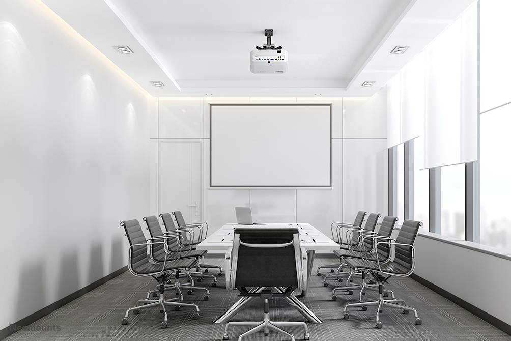 A modern conference room with a large table, several empty swivel chairs, a projector, and a screen on the wall.