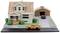 Miniature model of a detached house with an attached garage. An orange car is parked in the driveway.