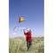 A girl in a red jumper flies a colourful kite in a grassy sand dune area on a sunny day.
