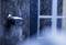 Security camera on a wooden wall, covered in snow and ice, gazing towards a snow-covered window. Wintry scene.