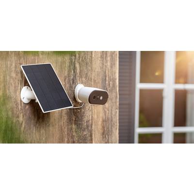 Outside camera and solar panel mounted on a house facade, with a window in the background.