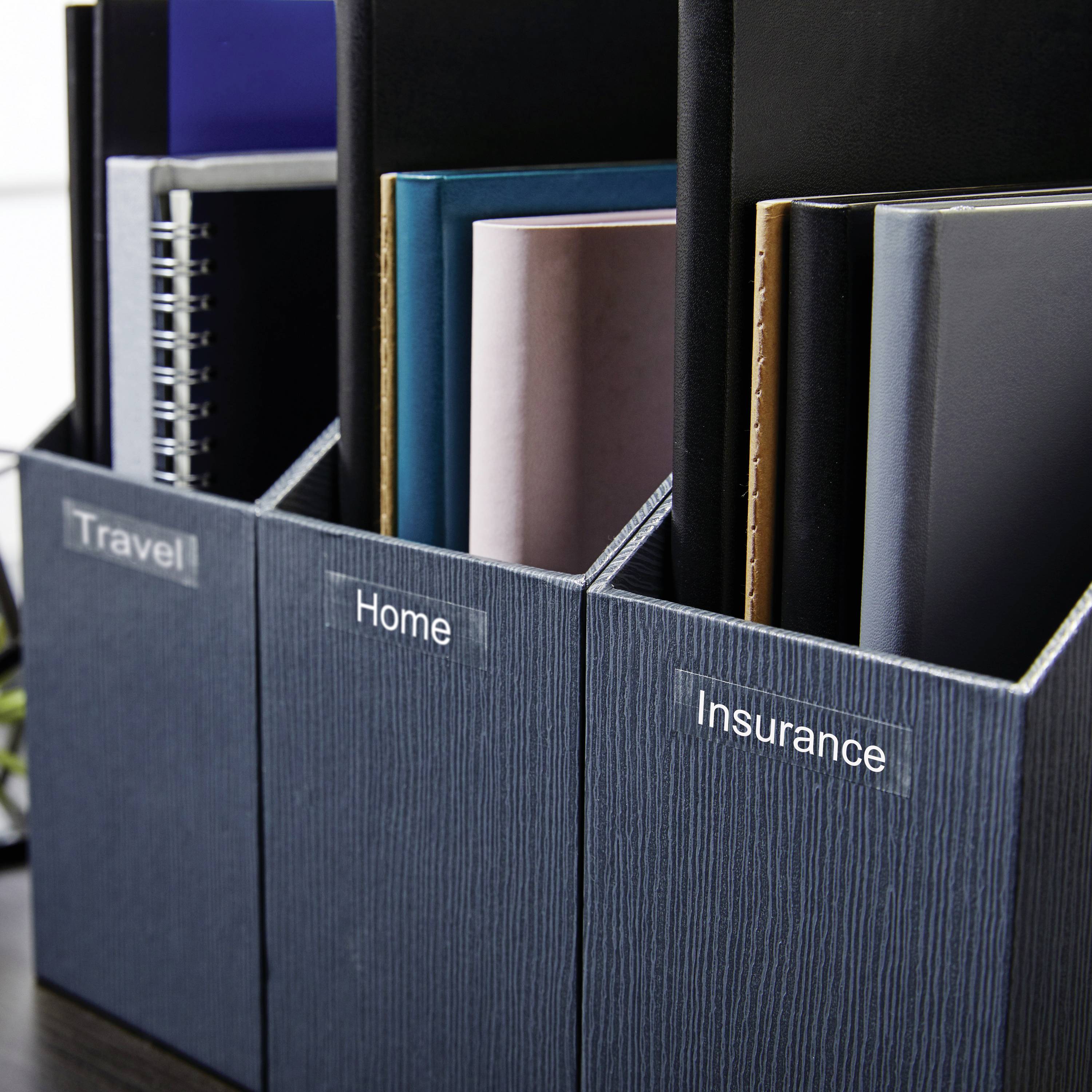 Several folders on a shelf, labelled 'Travel', 'Home' and 'Insurance', contain documents and notebooks.