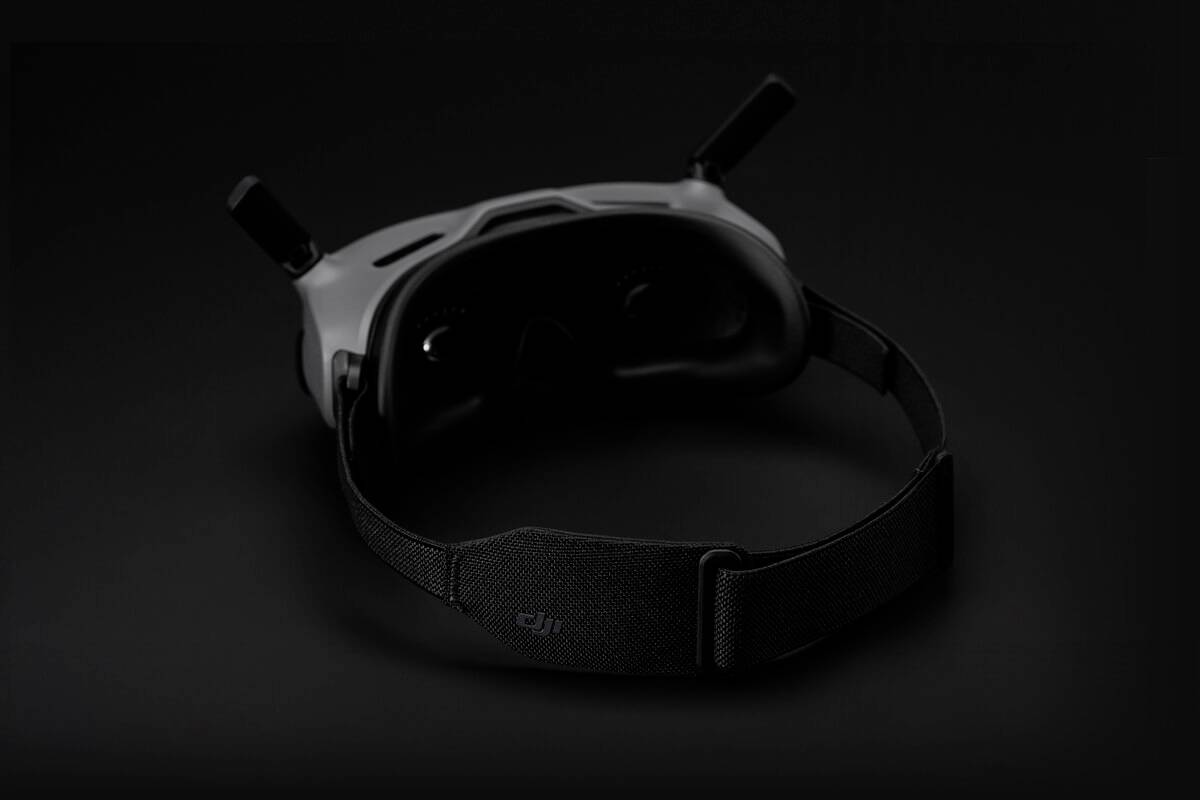 Virtual Reality headset with a black head strap against a dark background.