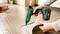 A person is using a cordless hot glue gun to adhere a piece of linoleum to a textured floor.