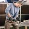 A man wearing safety glasses and ear protection is using an angle grinder to cut metal bars. Sparks are flying during the work.