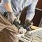 A person is cutting through metal with an angle grinder. Sparks are flying. The person is wearing protective clothing and gloves.