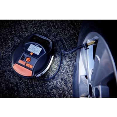 A digital tyre compressor is inflating a car tyre. The display shows '0.25' bar. A road forms the background.
