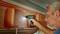 A man is using a cordless drill driver to secure a shelf in a motorhome. He is wearing safety glasses.