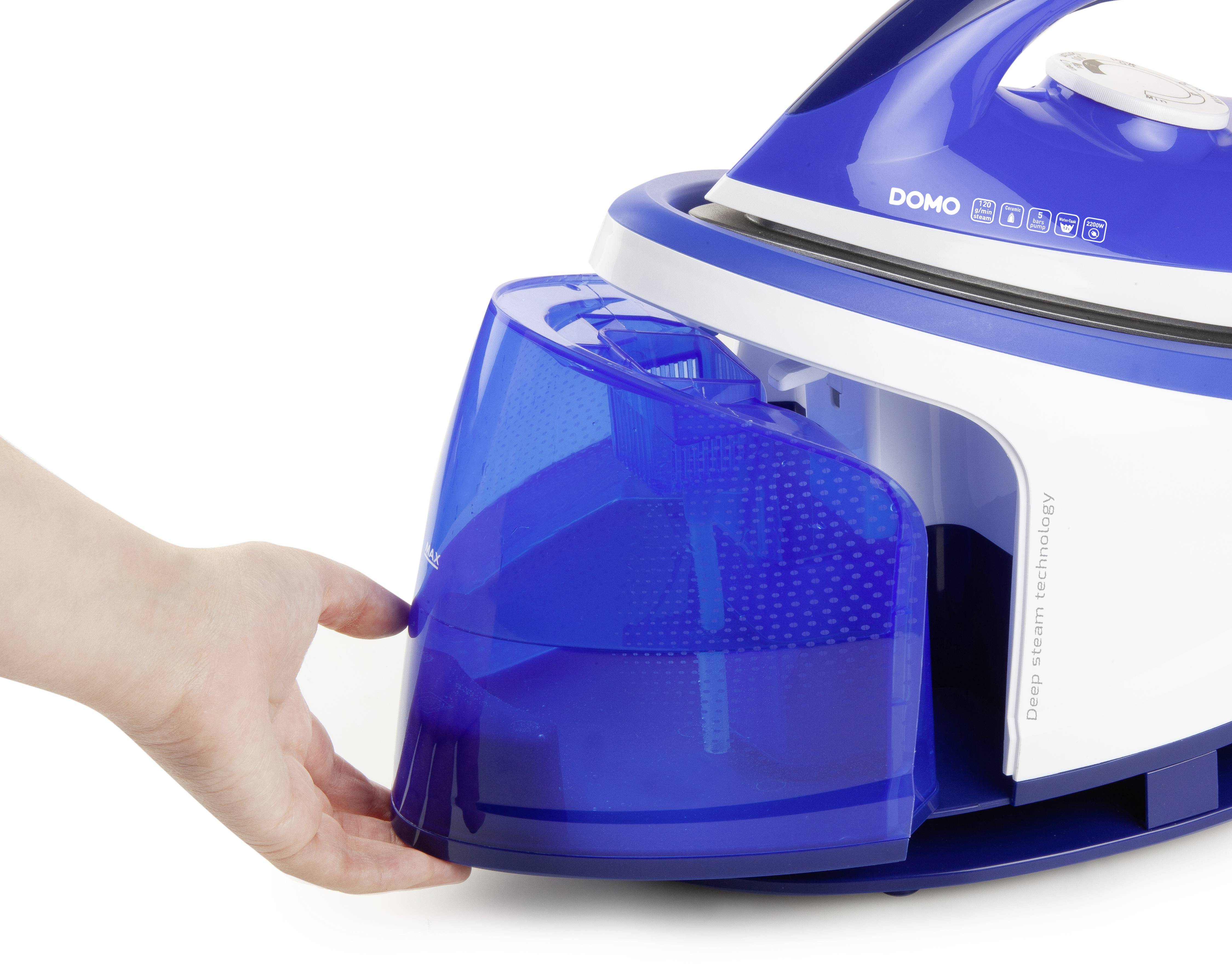 A hand reaches for the blue water container of a blue and white steam iron.