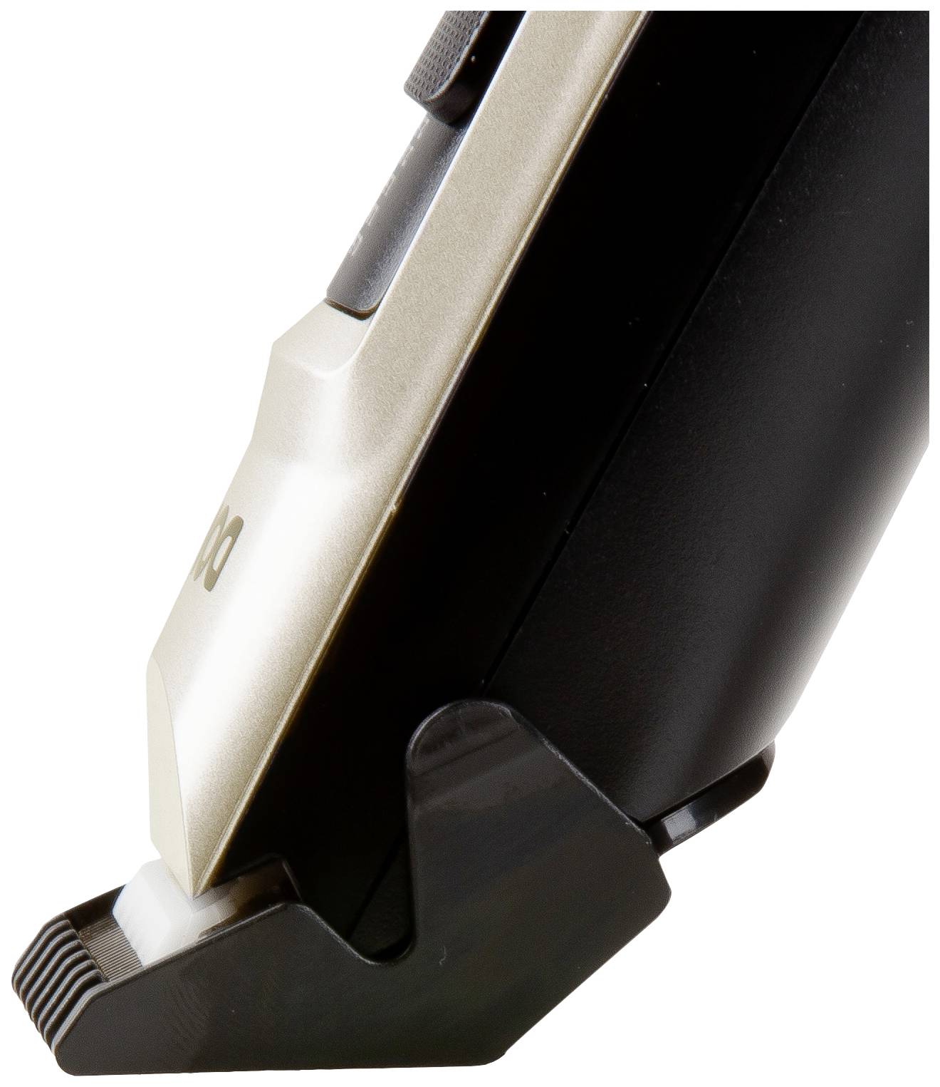 Electric hair clipper viewed from the side with an attachment comb, black handle and silver cutting head. Device is standing on a stand.