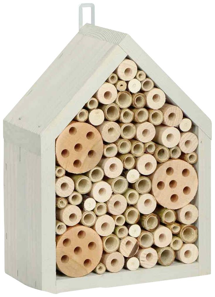 A wooden insect hotel in the shape of a house, featuring tubes and round wooden discs, serves as a shelter for insects.