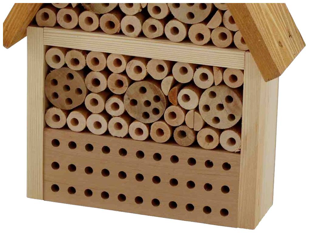 An insect hotel with various large holes in a wooden frame, providing nesting opportunities for wild bees.