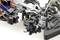 Close-up of a complex model car chassis with visible shock absorbers, springs, and electronic components.