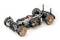 Remote-controlled model car chassis with visible suspension, motor and wiring on a white background.