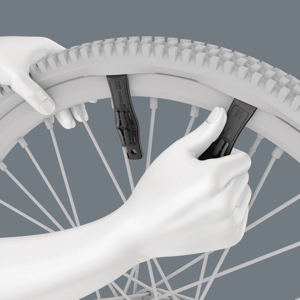 Hands are using two tyre levers to remove a bicycle tyre from the rim.