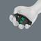 A hand holding a black ergonomic computer mouse with green accents on a gray background.