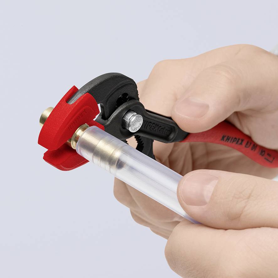 A hand is holding a small adjustable spanner attached to a transparent pipe.