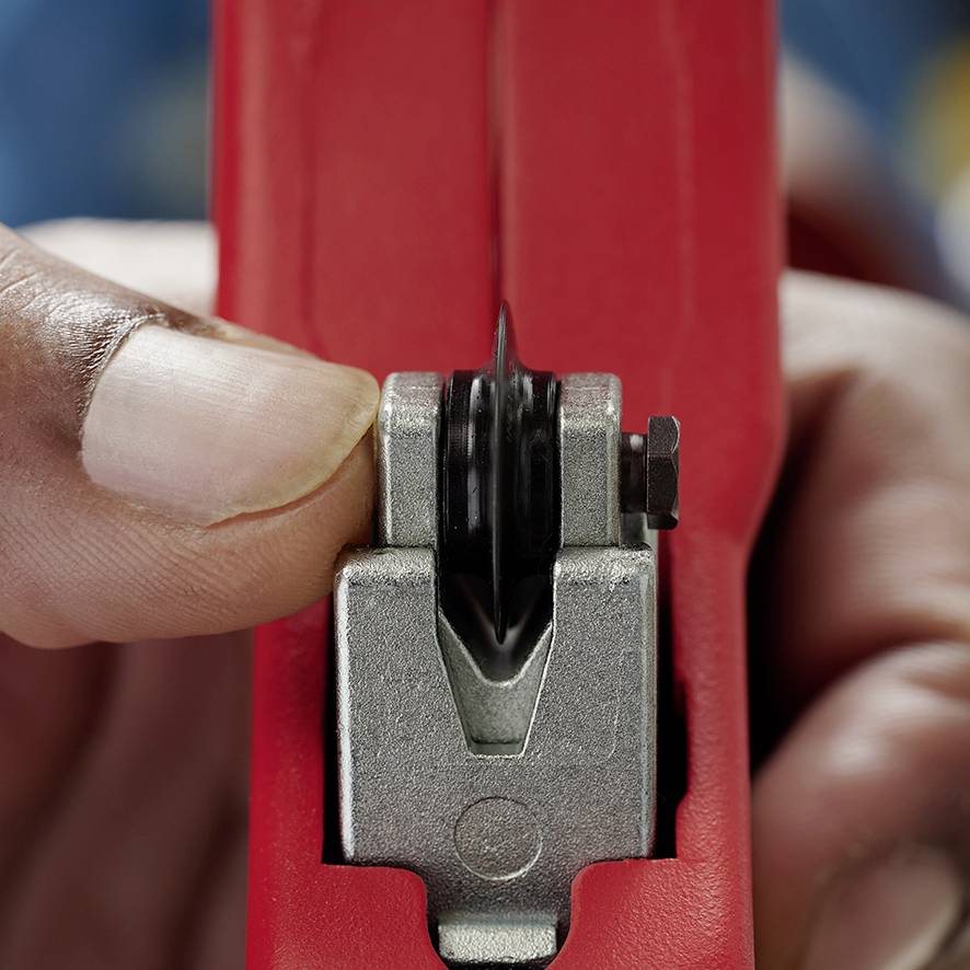 A hand is holding a red tape dispenser, ready to cut a piece of tape.