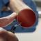 A hand is holding a copper pipe which is being deburred with a deburring tool to remove sharp edges.