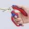 A hand is holding a blue and red multi-purpose pliers, cutting a yellow cable. The pliers are branded with the 'Knipex' logo.