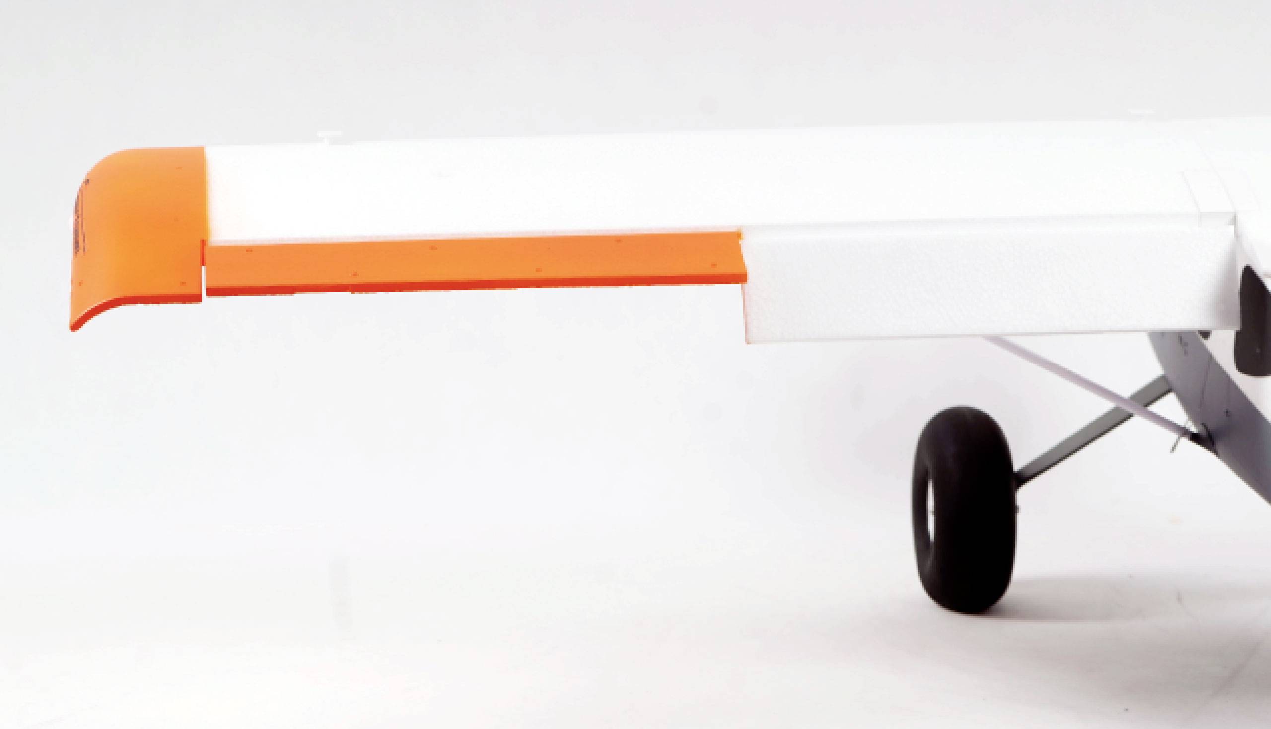 A white aircraft wing with an orange tip and part of the landing gear is visible. The background is light.