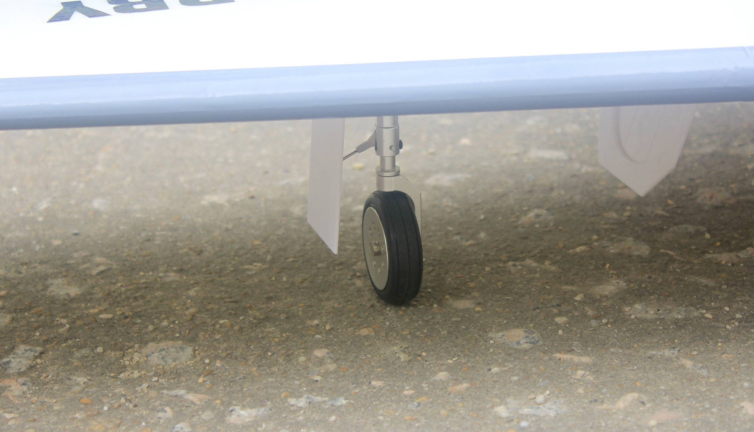 A small aircraft undercarriage on a concrete surface. Main focus on the wheel and lower aircraft structure.