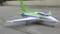 A model aircraft in light green and white paintwork is standing on a concrete surface. It has retractable landing gear and an aerodynamic fuselage.