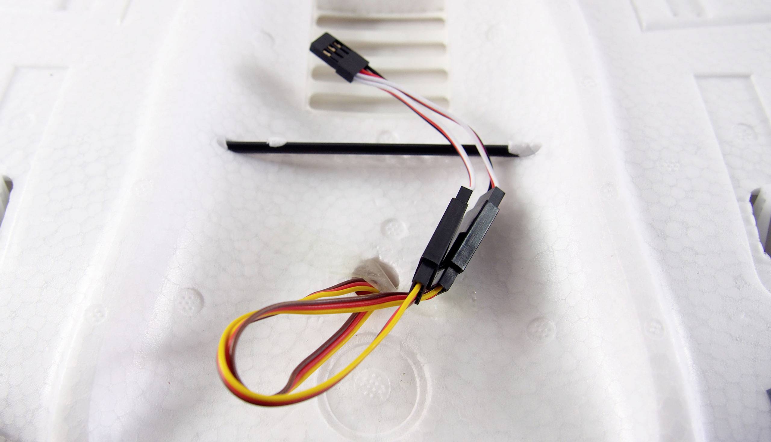 Multicoloured cables with plugs on a white, textured surface. They appear to be intended for electronic connections.